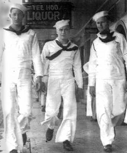 USS Navy sailors walk on the sidewalk in downtown Honolulu